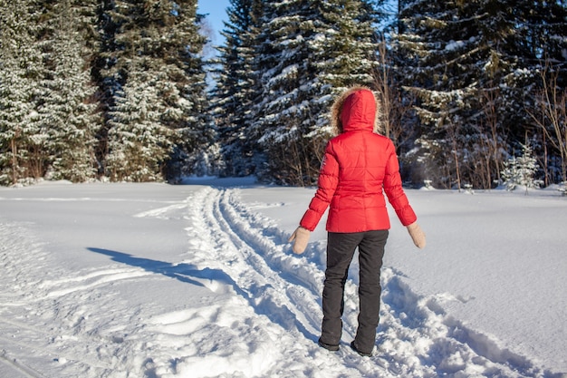 Een meisje in een rood jasje loopt door een besneeuwd bos