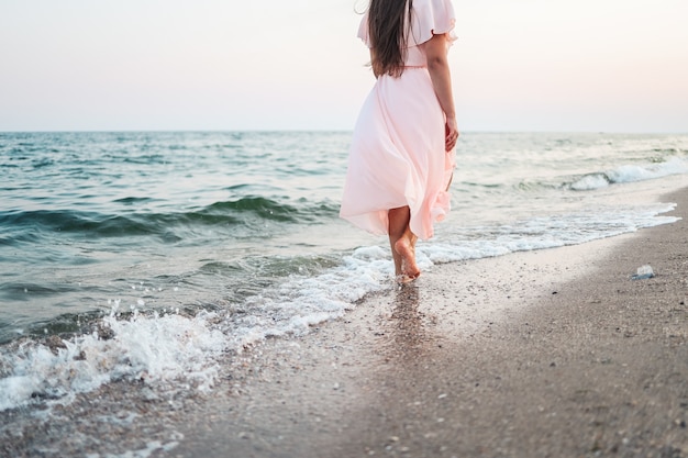 Een meisje in een roze jurk rent langs de kust