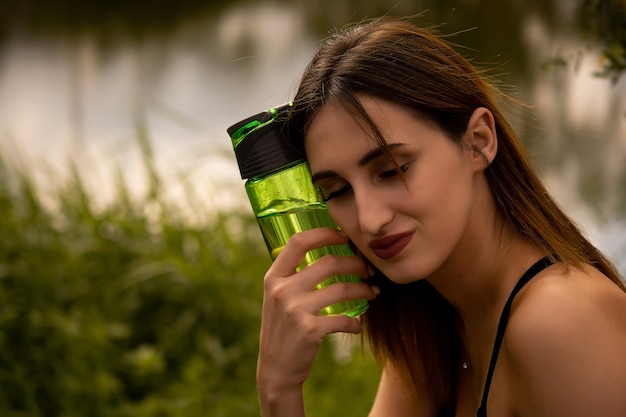 een meisje in een sportuniform houdt een fles in haar hand, een meisje drinkt water uit een fles