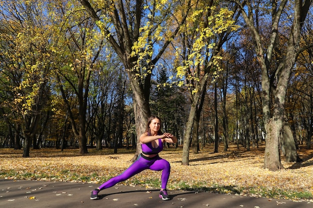 Een meisje in een trainingspak warmt zich op in het park voordat ze gaat rennen. Sporten in de frisse lucht