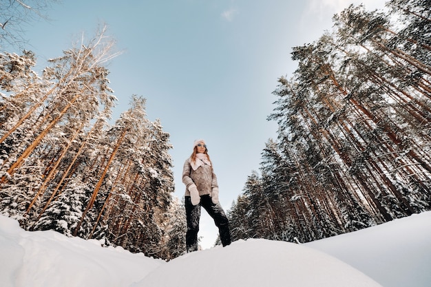 Een meisje in een trui en wanten in de winter staat op een besneeuwde achtergrond.