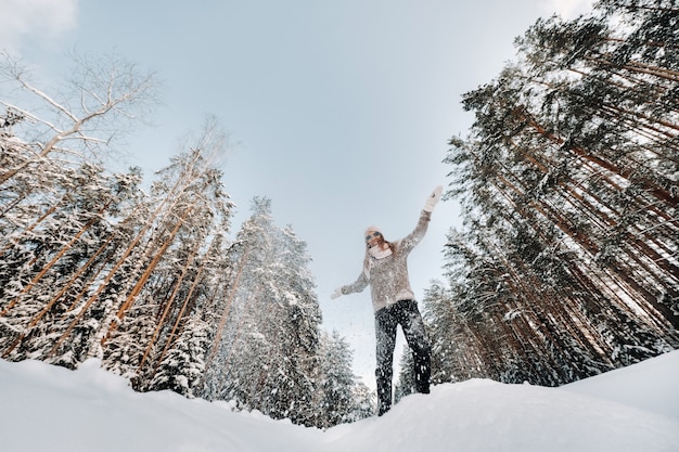 Een meisje in een trui en wanten in de winter staat op een besneeuwde achtergrond