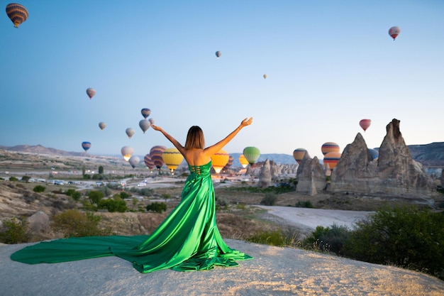 Een meisje in een vliegende jurk met een lange trein op de achtergrond van ballonnen in Cappadocië