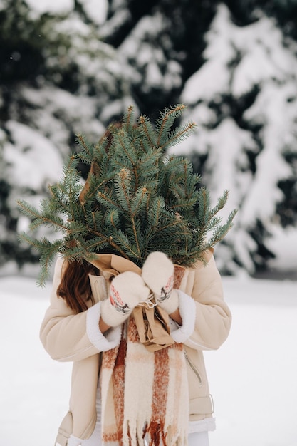 Een meisje in een winterbos met een boeket dennentakken Besneeuwde winter