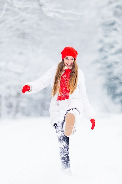 Een meisje in een winterjas speelt met sneeuw