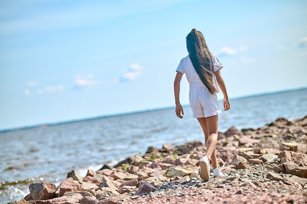 Een meisje in een witte jurk die op een strand loopt