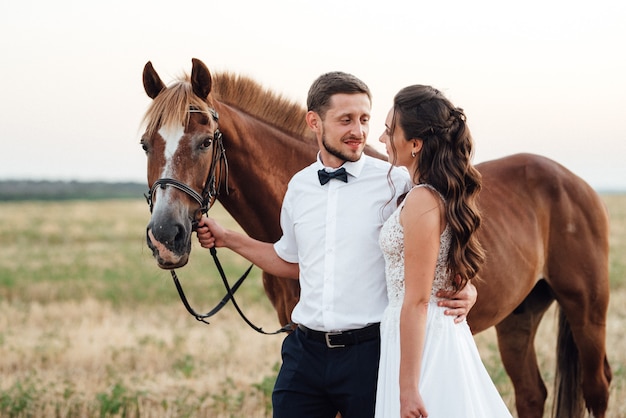 Een meisje in een witte jurk en een man in een wit overhemd op een wandeling met bruine paarden in het dorp