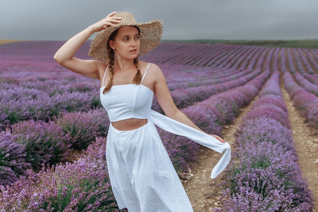 Een meisje in een witte jurk en een strohoed in een lavendelveld