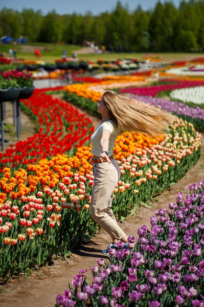 Een meisje in een witte jurk rent tussen de tulpen Veld met gele en rode tulpen