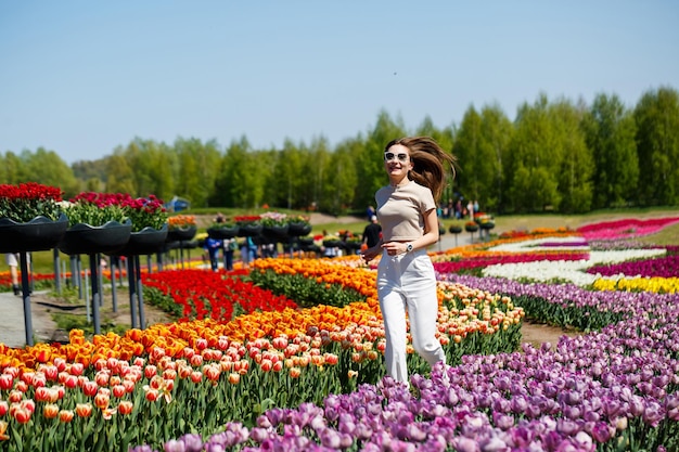 Een meisje in een witte jurk rent tussen de tulpen Veld met gele en rode tulpen