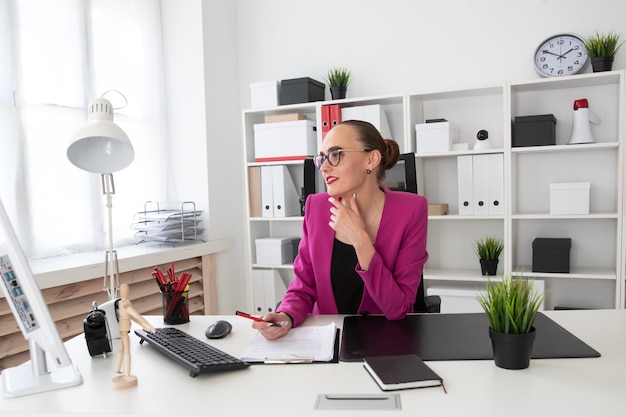 Een meisje in een zakelijke stijl werkt op een computer op kantoor