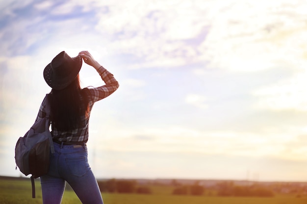 Een meisje in jeans en een hoed reist de zomer door het land