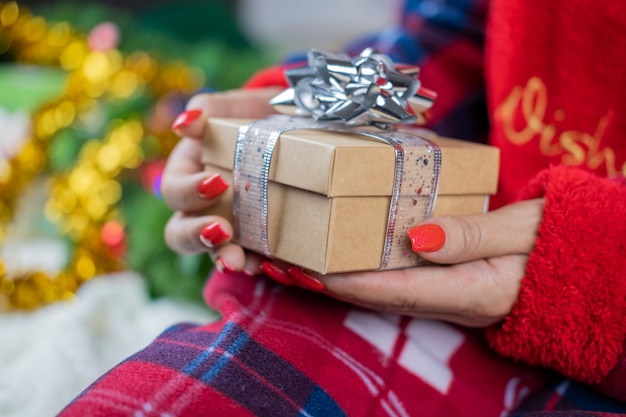 een meisje in pyjama's van de kerstman met een doos met verrassingsgeschenk
