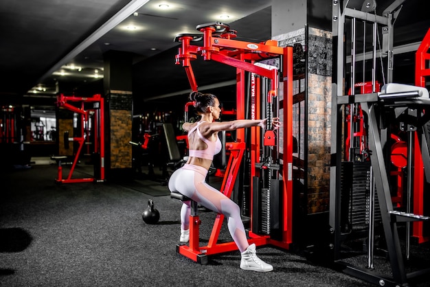 Een meisje in sportkleding in een professionele sportschool traint met fitnessapparatuur