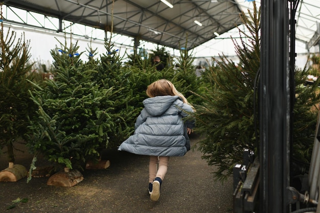 Een meisje kiest een Normandische kerstboom in een winkel