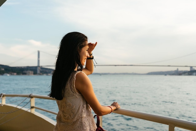 Een meisje kijkt naar de zonsondergang in de zee, op zoek naar iets in de verte, een brug over de Bosporus