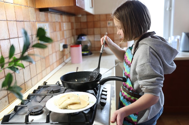 Een meisje kookt pannenkoeken in de keuken