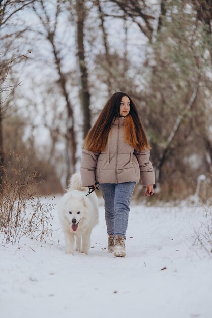 Een meisje loopt met haar geliefde huisdier Samoyed in de winter aan de oever van een meer in het park Wandelen met de hond in de winter