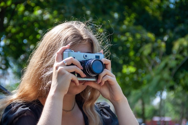 een meisje maakt foto's, een meisje gebruikt een camera, een camera in haar handen, een man in het park, hobby's, foto