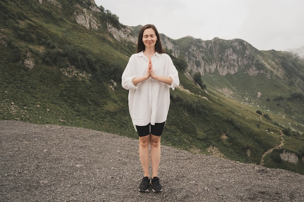 Een meisje mediteert in de bergen yoga retraite in de natuur een meisje in een wit overhemd geniet van de pr...