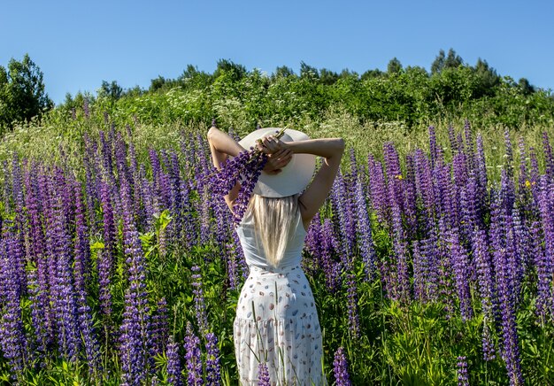 Een meisje met blond haar in een veld met lupinen