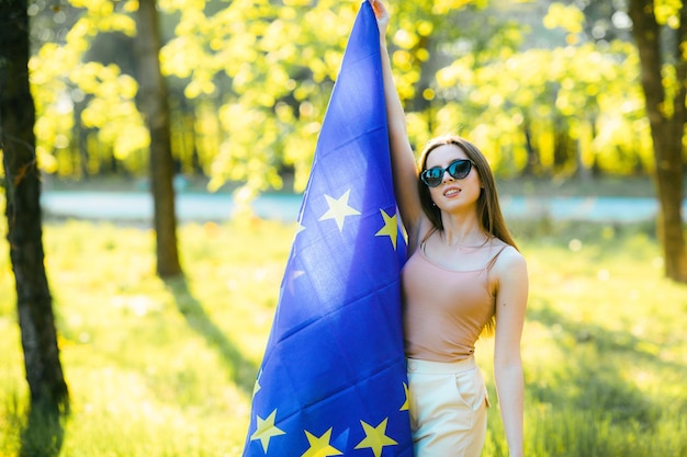 een meisje met bruin haar poseert met de vlag van de europese unie