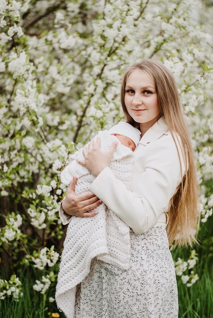 een meisje met een baby in haar armen moeder houdt de baby moeder en kind vast in een bloeiende tuin