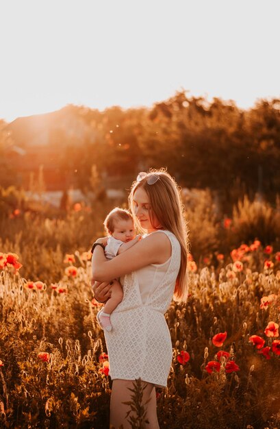Een meisje met een baby Moeder en baby De ondergaande zon Poppy bloemen Moeder houdt de baby in haar armen