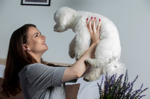 Een meisje met een bichon-hond speelt thuis eigenaar met een schattige hond