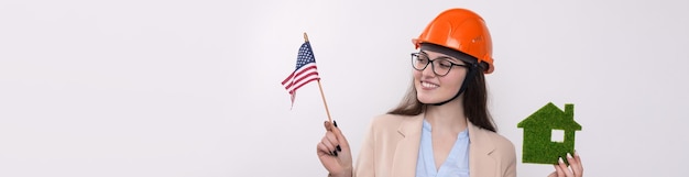 Een meisje met een bouwhelm en een Amerikaanse vlag heeft een groen eco-huis