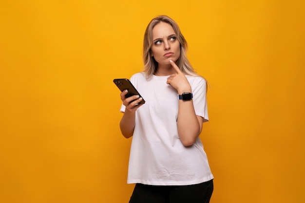 Een meisje met een gadget in haar handen plaatst een bestelling op internet op een gele achtergrond