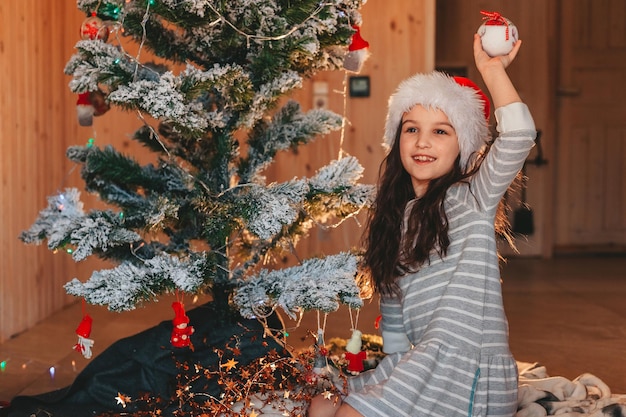 Een meisje met een kerstmuts speelt thuis met kerstspeelgoed