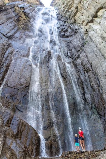 Een meisje met een kind op de achtergrond van de AbaiSu-waterval KabardinoBalkarië juni 2021