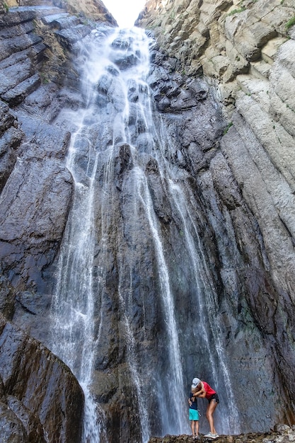 Een meisje met een kind op de achtergrond van de AbaiSu-waterval KabardinoBalkarië juni 2021