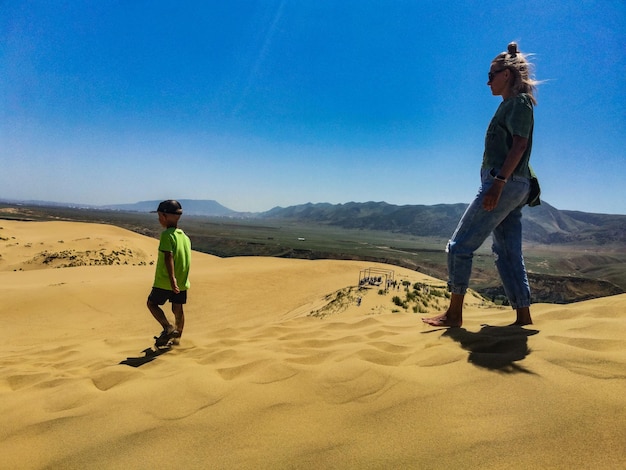 Een meisje met een kind op de zandduinen van sarykum een natuurmonument dagestan rusland