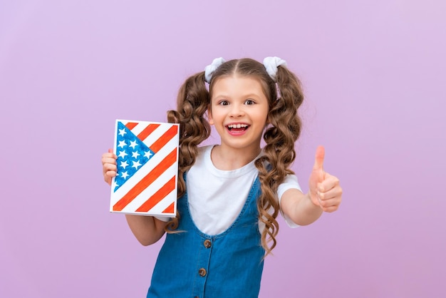 Een meisje met een leerboek met de afbeelding van de Amerikaanse vlag een kind studeert graag in het buitenland In het buitenland wonen en een diploma behalen