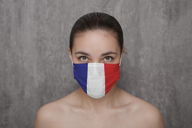 Een meisje met een masker op haar gezicht met de vlag van Frankrijk