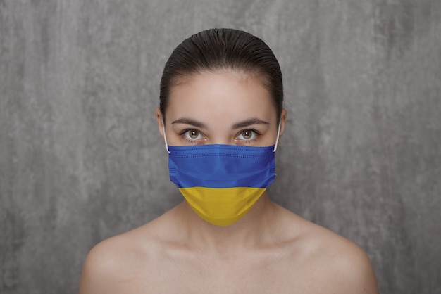 Een meisje met een masker op haar gezicht met een vlag van Oekraïne