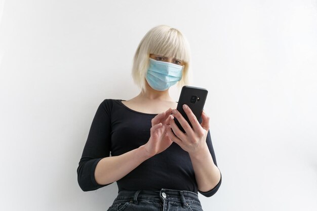 Een meisje met een medisch masker dat een mobiele telefoon vasthoudt