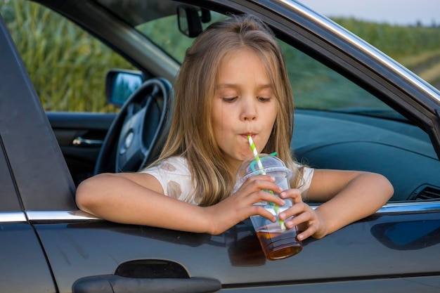 Een meisje met een plastic glas van een cocktail in een auto