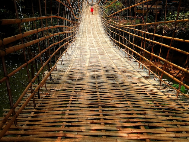 Een meisje met een rood pak lopen op bamboe brug