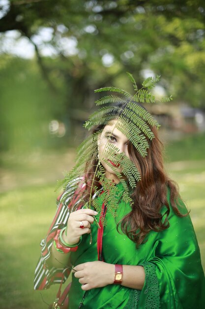 Foto een meisje met een saree die haar gezicht verbergt met een blad