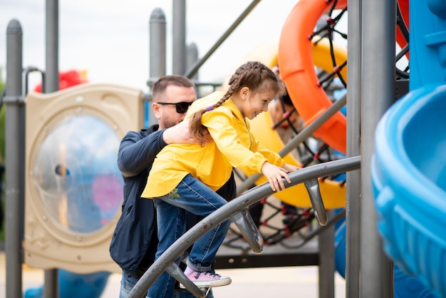 Een meisje met haar vader op de speelplaats Papa helpt het meisje de trap op te klimmen Tijd met familie Stad