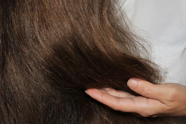 Een meisje met lang donker haar houdt krullen in haar hand Haarverzorging Probleem met haaruitval