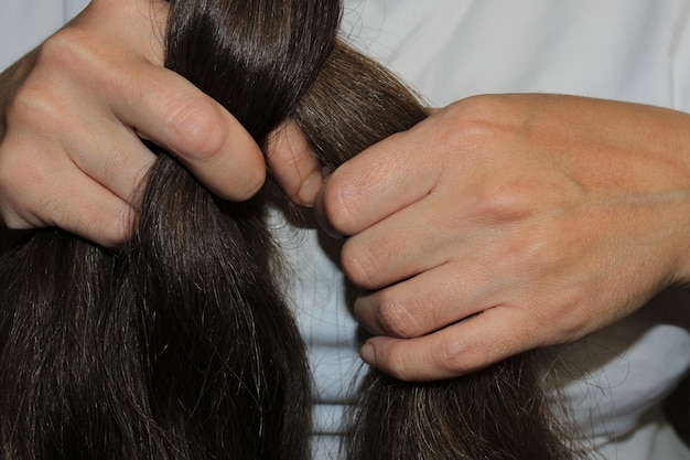 Een meisje met lang donker haar vlecht haar haar Close-up handen Haarverzorging Probleem met haaruitval