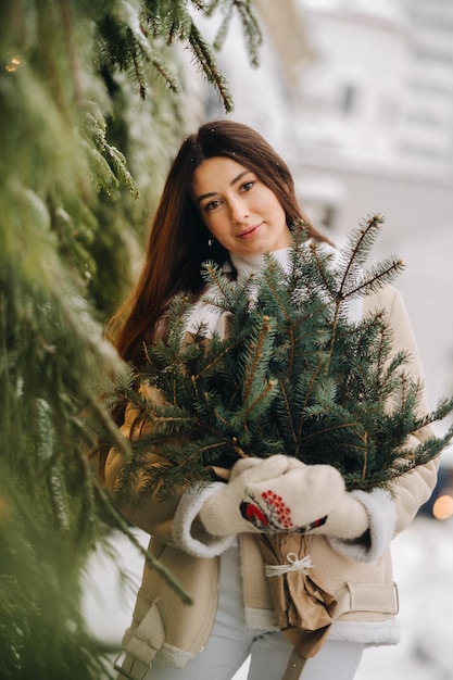 Een meisje met lang haar in de winter op straat met een boeket verse dennentakken