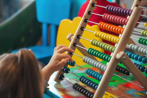 Een meisje met lang haar rekent op veelkleurige telraam in de kinderruimte