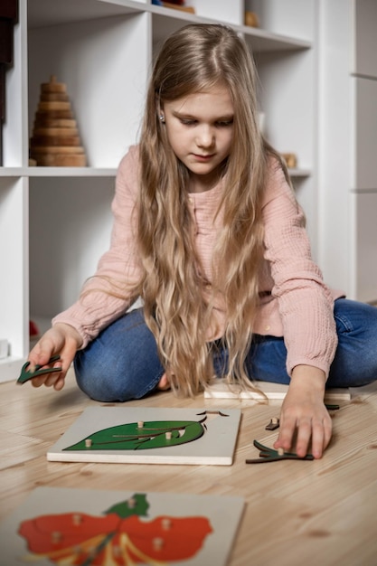 Een meisje met lang haar voegt een montessori-puzzel toe aan de samenstelling van de plant