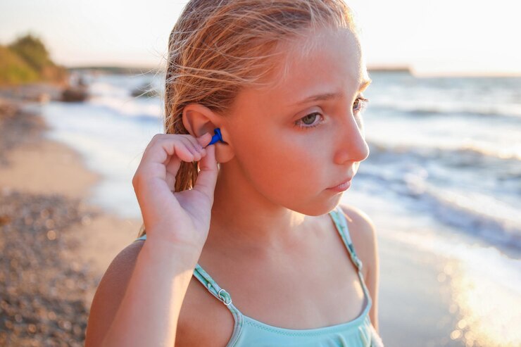 Een meisje met oordopjes van water in haar oren op het strand