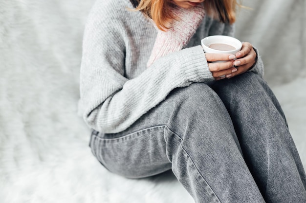 Een meisje met winterkleren die in de winter thuis genieten van een kop warme chocolademelk